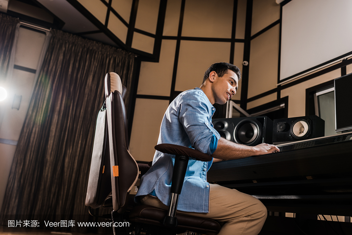 英俊的混合種族聲音制作人在錄音室混音控制臺(tái)工作